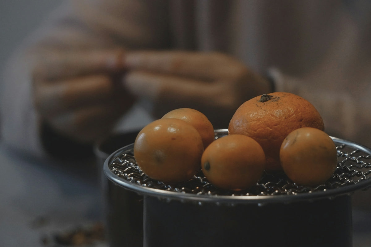 a metal container filled with oranges on top of a table
